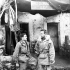 Canadians and Americans wear the same uniform in the First Special Service Force. Lieut. J. Kostelec (Calgary, AB) and Lieut. H.C. Wilson (Olympia, WA) resting on the steps of the Force's Clearing Station, near Venafro, Italy, January 1944.