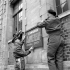 Lieutenant-Colonel R.S. Malone (left) helping to erect the sign at the editorial office of the Maple Leaf newspaper, Caen, France, 11 July 1944.