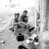 War correspondents Greg Clark of the Toronto Star and Ralph Allen of The Globe and Mail cooking Clark's birthday breakfast in the courtyard of a castle, Castello di Lagopesole, Italy, 25 September 1943.