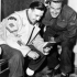 Lance-Corporal S. Walker and Corporal E. Hoole, Canadian Provost Corps, looking at photos of their families while preparing for Christmas leave in Canada. Riccione, Italy, 1 December 1944.