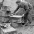 Gunner Russ Kannett of the Royal Canadian Artillery (R.C.A.) selecting a 4.5-inch shell charge case to be converted into a stove, Ravenna, Italy, 10 February 1945.