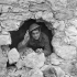 Private J.A. Robb of The Loyal Edmonton Regiment looking through a shell hole in the foundation of a building, Colle d'Anchise, Italy, 27 October 1943.